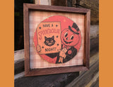 A square framed decorative sign with a vintage Halloween illustration. The artwork shows a smiling jack-o'-lantern in a top hat holding a sign that reads 'HAVE A Spooktacular NIGHT!' with a black cat.